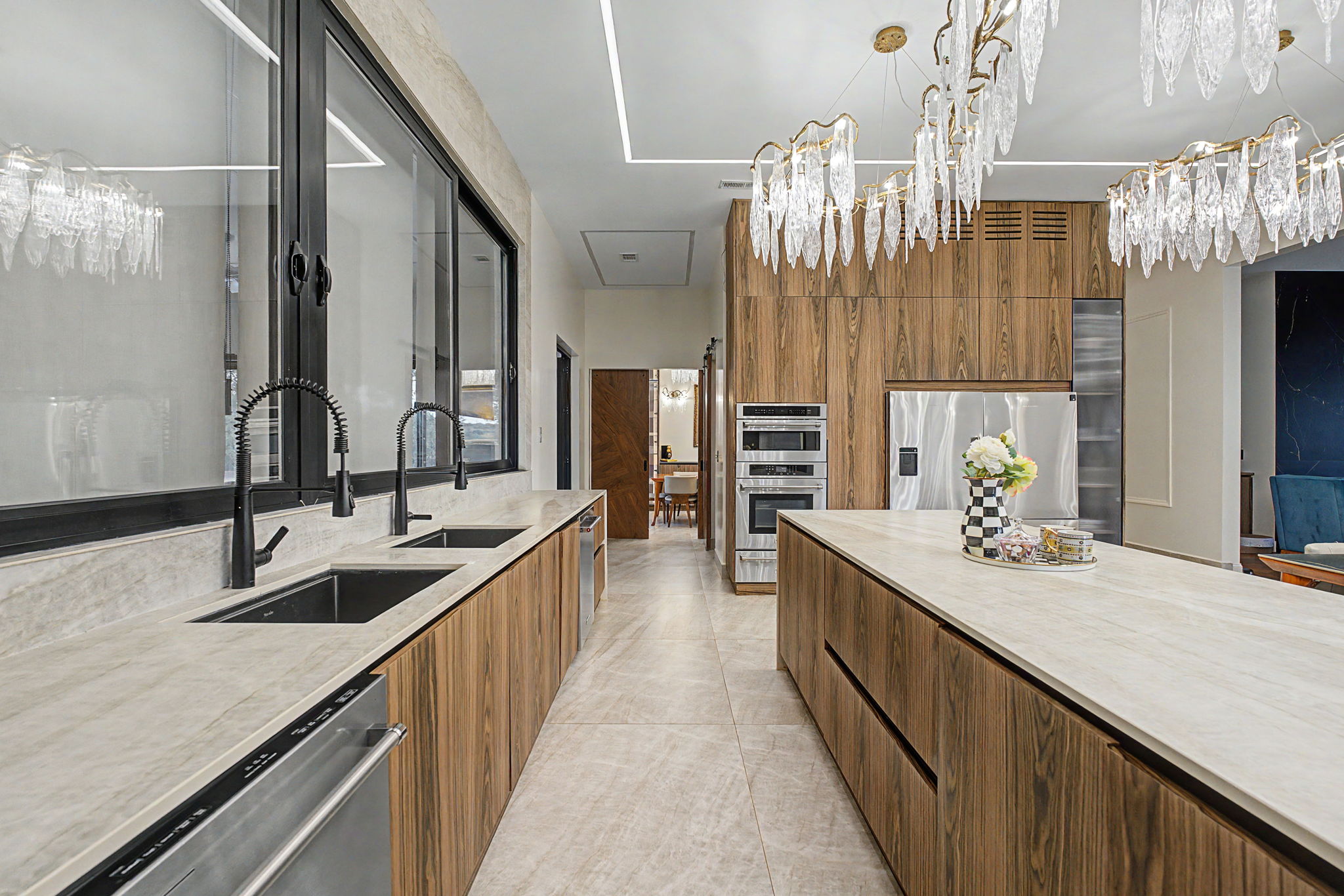Custom walnut kitchen with porcelain surfaces, dual sinks and sculptural lighting